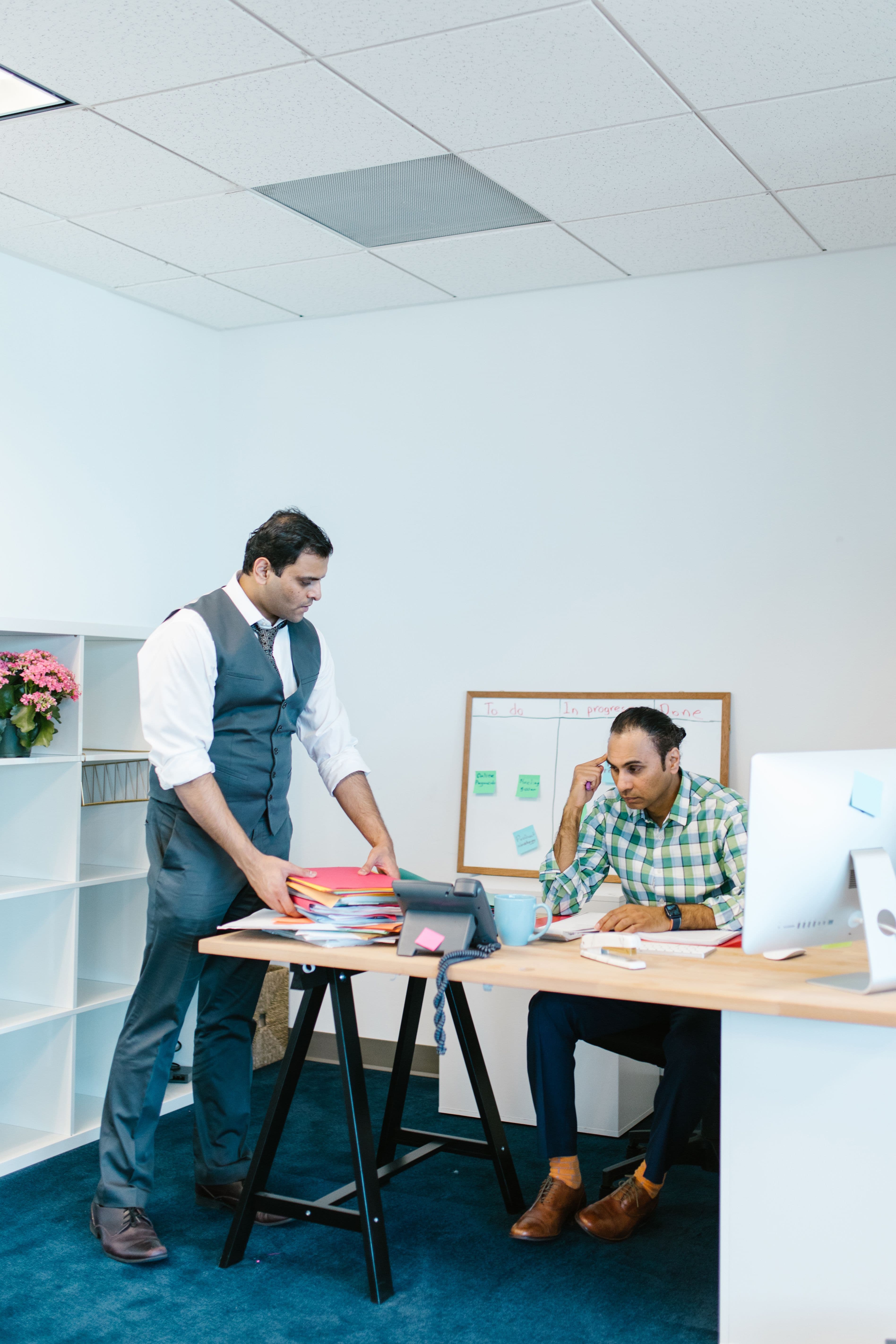 Two colleagues reviewing project progress on a task board in a modern office